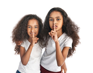 Cute African-American girls showing silence gesture on white background