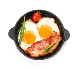 Frying pan with eggs and bacon on white background