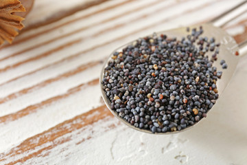 Fototapeta na wymiar Scoop with poppy seeds on wooden table, closeup