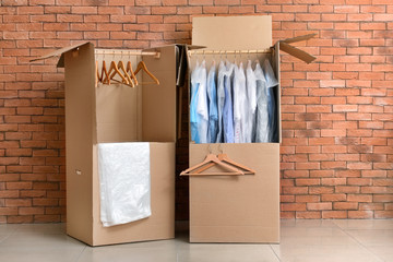 Wardrobe boxes with clothes near brick wall