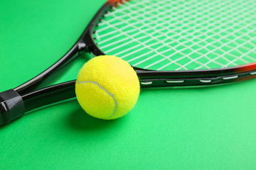 Tennis racket and ball on color background, closeup