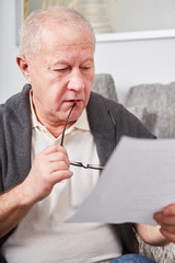 Besorgter Senior liest eine Rechnung