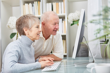 Paar Senioren schaut neugierig auf PC Monitor