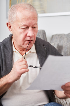 Besorgter Senior liest eine Rechnung