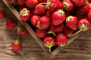 Box with ripe red strawberry on wooden background
