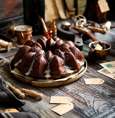 Delicious homemade chocolate bundt cake on wooden plate stands on rustic table