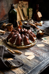 Delicious homemade chocolate bundt cake on wooden plate stands on rustic table