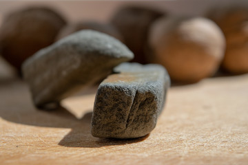 Two stones on a cutting board close-up, behind walnuts