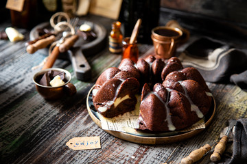 Delicious homemade chocolate bundt cake on wooden plate stands on rustic table