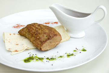 grilled meat on a white plate, sauceboat with sauce, restaurant serving
