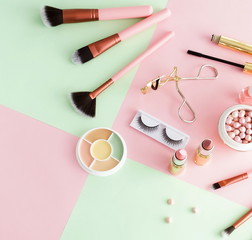 Makeup products, decorative cosmetics on pastel color pink mint background  flat lay.  Fashion and beauty concept. Top view. Copy space.