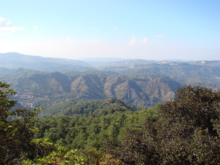 A panorama from the height of the mountain is a barely cloudy blue sky that stretches to the horizon over endless mountain ranges covered with forest.