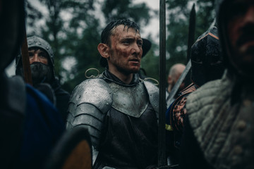 Squad of medieval knights of the Crusaders stand in armors and helmets.