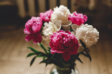 Beautiful pink and white peonies on rustic wooden floor with old glass jar and scissors. Copy space. Floral decor and arrangement. Gathering flowers. Rural still life, countryside flowers