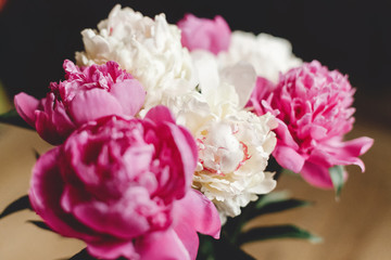 Beautiful pink and white peonies bouquet in glass jar on rustic wooden floor , flat lay. Floral decor and arrangement. Gathering flowers. Rural still life, countryside flowers