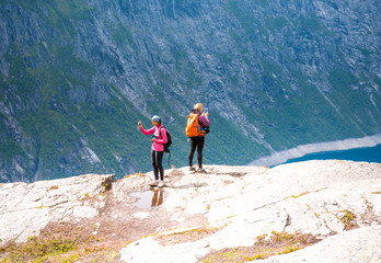 Fototapeta premium Two sporty women on the edge of Norway fjord making photo
