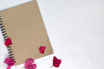 Craft cover notebook with pink flowers on white handmade fiber paper background. Flat lay, top view, copy space, mock up