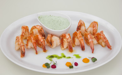 shrimps with a beautiful crust on a white plate, sauceboat with sauce, restaurant serving