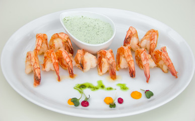 shrimps with a beautiful crust on a white plate, sauceboat with sauce, restaurant serving