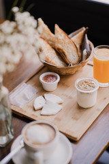 desayuno completo en una tabla de madera con zumo de naranja, cafe y tostadas