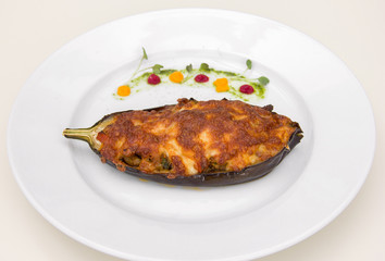 stuffed eggplant baked with cheese, restaurant serving. on a white plate