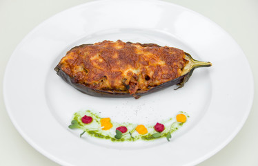 stuffed eggplant baked with cheese, restaurant serving. on a white plate