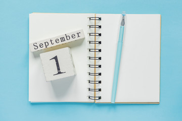 September 1 on a wooden calendar on study textbook on  blue background. Back to school concept
