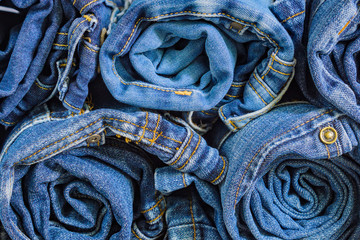 roll blue denim jeans arranged in stack, background texture. Beauty and fashion clothing concept