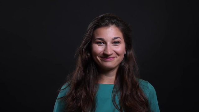 Closeup portrait of young pretty brunette female smiling with confidence looking at camera with background isolated on black