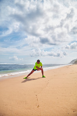 Fototapeta na wymiar Sportsman stretching on a tropical sandy beach.