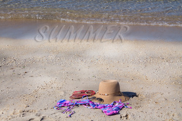 summer accessories on the beach, hat, sunglasses, bikini and footwear, concept of vacation and relaxation