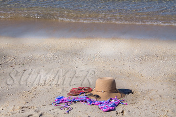 summer accessories on the beach, hat, sunglasses, bikini and footwear, concept of vacation and relaxation