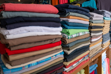 Clothes that are arranged on shelves and hangers.