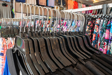 Clothes that are arranged on shelves and hangers.