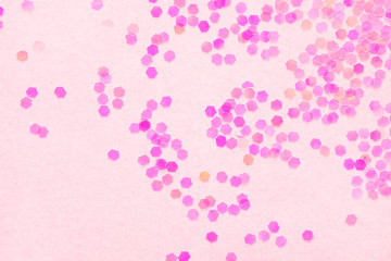 Confetti on pink paper background, festive concept.