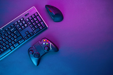Keyboard, mouse and joystick on violet table background.