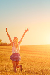 Young woman jumping and running in a wheat field.