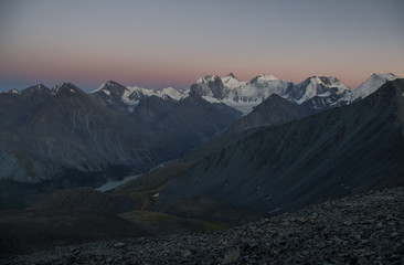 Dark desert night mountain valley with ranges of  snow peaks on a horizon in a twilight