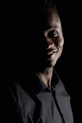 Naklejka na ściany i meble portrait of a african man on black background, smiling