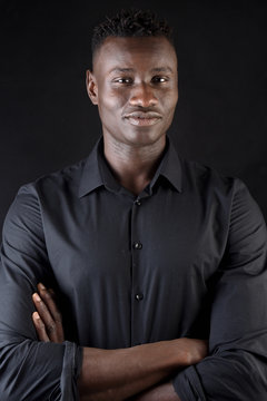 portrait of a african man arms crossed on black background