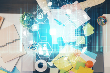 Social network theme hologram over hands taking notes background. Concept of global international people connect. Double exposure