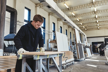 Busy carpenter in uniform working with wood.