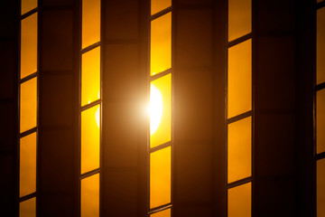 The sun is reflected in the yellow glass surface of a modern building.