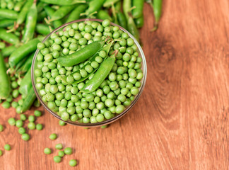 Green closeup peas on the wooden floor.