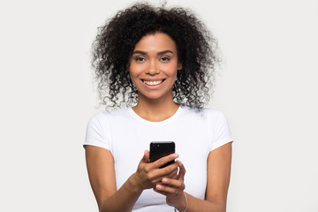 Headshot portrait smiling african woman holding smartphone looking at camera