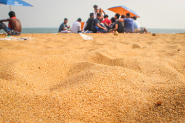 Fototapeta na wymiar A group of people enjoying the sun at the sandy beach of Goa. People with umbrellas on a beach.