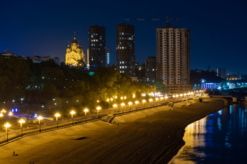 Fototapeta na wymiar Night View of the city of Khabarovsk from the Amur river. Blue night sky. The night city is brightly lit with lanterns.