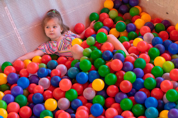 Fototapeta na wymiar Little girl playing with colorful plastic balls on the playground. Top view