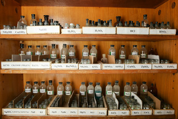 bottles with solutions are on the shelf of the chemical cabinet.