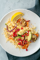 Couscous with roasted vegetables on white plate, top view